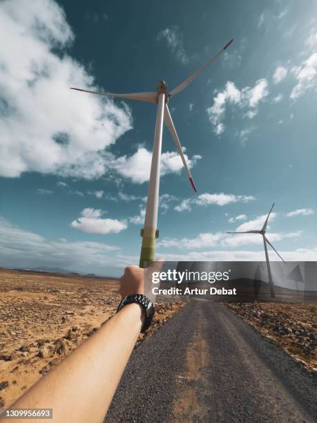 creative picture holding electric wind turbine generator from personal perspective like pinwheel. - paper windmill stock-fotos und bilder