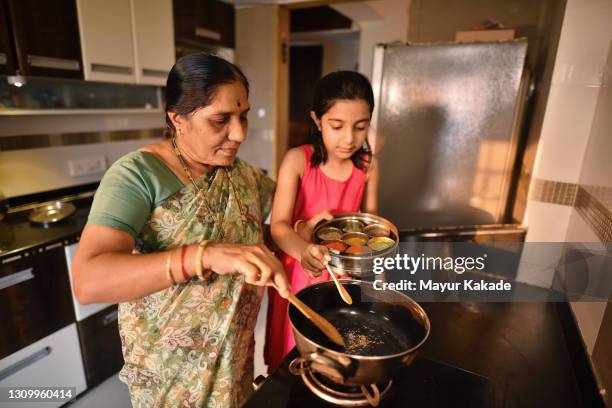 girl helping her grandmother in cooking - daily life in india stockfoto's en -beelden