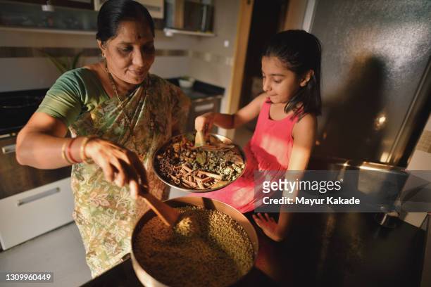girl helping her grandmother in making spices - indian spices stockfoto's en -beelden