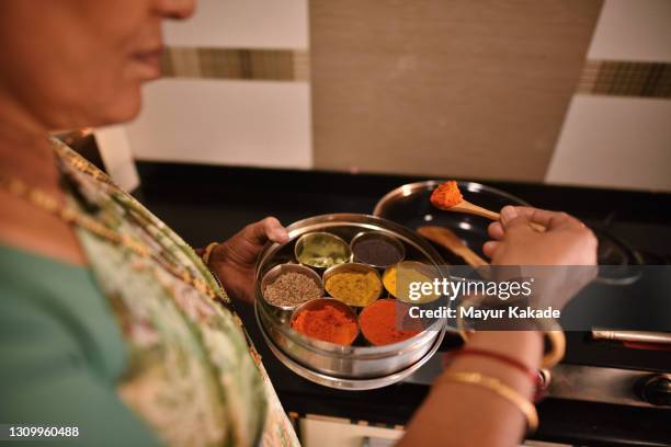 mujer que usa especias mientras cocina alimentos - comida india fotografías e imágenes de stock