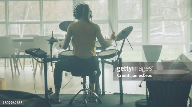 young woman practicing on electronic drums in her living room - playing drums stock pictures, royalty-free photos & images