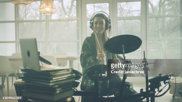 young woman practicing on electronic drums in her living room. online lesson - drum kit stock pictures, royalty-free photos & images