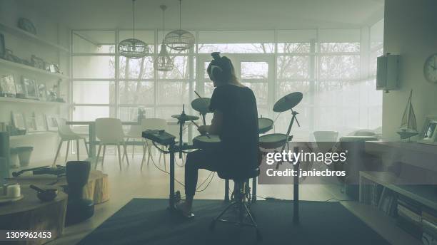 young woman practicing on electronic drums in her living room - playing drums stock pictures, royalty-free photos & images