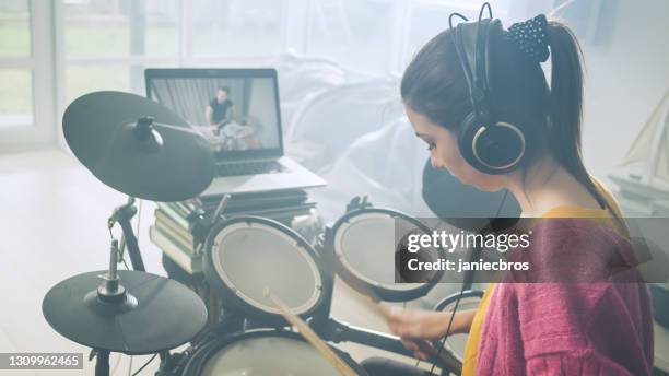 young woman practicing on electronic drums in her living room. online lesson - drummer isolated stock pictures, royalty-free photos & images