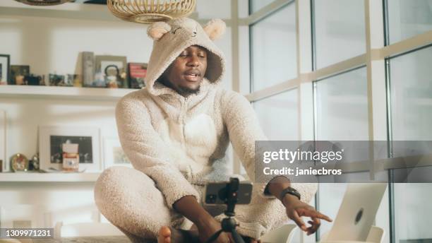 missing a friend during lockdown. african man doing video call in cute bear onesie. using smart phone - bodysuit stock pictures, royalty-free photos & images