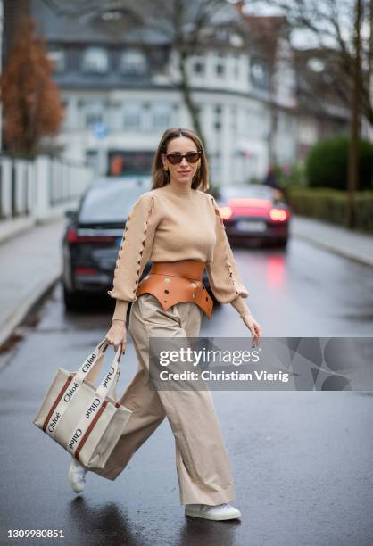 Alexandra Lapp is seen wearing LOEWE cut-out Obi belt in tan, CHLOÈ knitted jumper in beige, LOEWE pleated wide trousers in beige, CHLOÈ Woody...