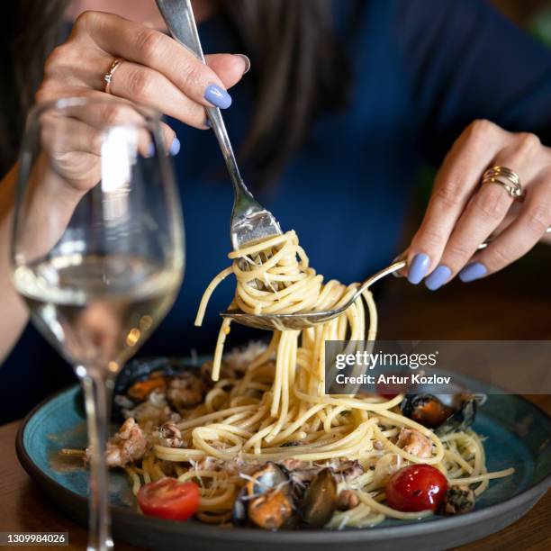spaghetti with mussels. woman winds on fork seafood and italian pasta. close up shot. healthy exotic lunch. soft focus - close up cooking stock-fotos und bilder