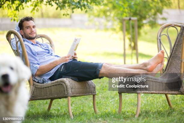 man reading newspaper in the garden. - man garden chair stock pictures, royalty-free photos & images