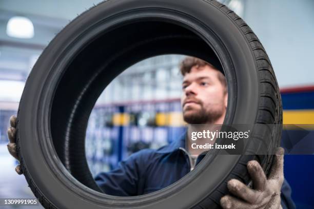 mecánico de coches revisando neumático - neumaticos fotografías e imágenes de stock