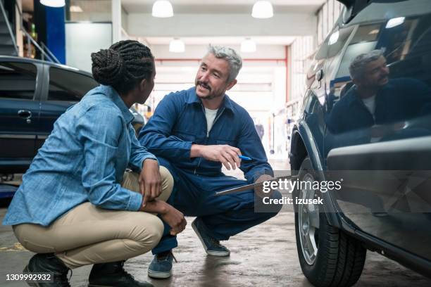 mecánico de coches hablando con el cliente - garaje de reparación fotografías e imágenes de stock