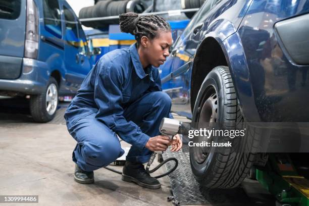 female car mechanic changing wheel - machinery imagens e fotografias de stock
