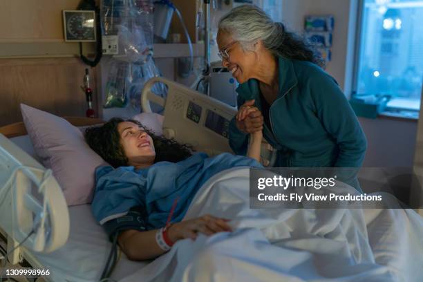 ethnic mother in hospital bed waiting to give birth with mother at her side - delivery room stock pictures, royalty-free photos & images