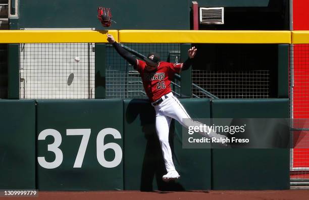 Right fielder Pavin Smith of the Arizona Diamondbacks loses his glove as he leaps against the fence in an attempt to catch a home run ball hit by...
