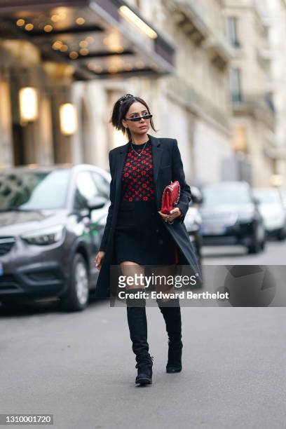 Patricia Gloria Contreras wears sunglasses, a necklace, a Vuitton red and black monogram print dress, a black long coat, a red quilted leather Chanel...