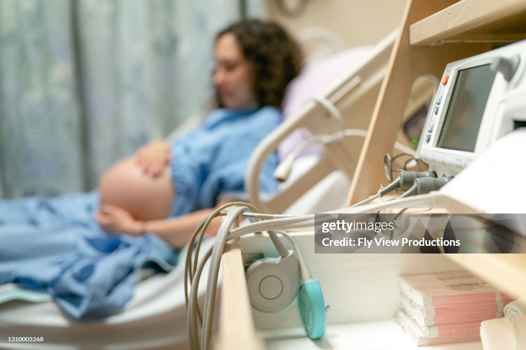 Pregnant Mother Laying In Hospital Bed While Hooked Up To CTG Machine