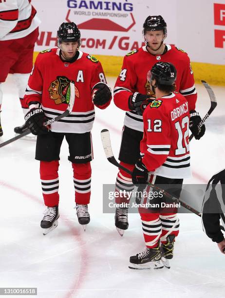 Patrick Kane and Carl Soderberg of the Chicago Blackhawks skate in to congratulate Alex DeBrincat after Debrincat scored a second period goal against...