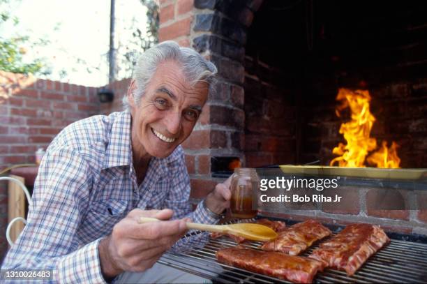Rory Calhoun enjoys cooking BBQ ribs on his outdoor grill at home, February 22,1985 in Los Angeles, California.