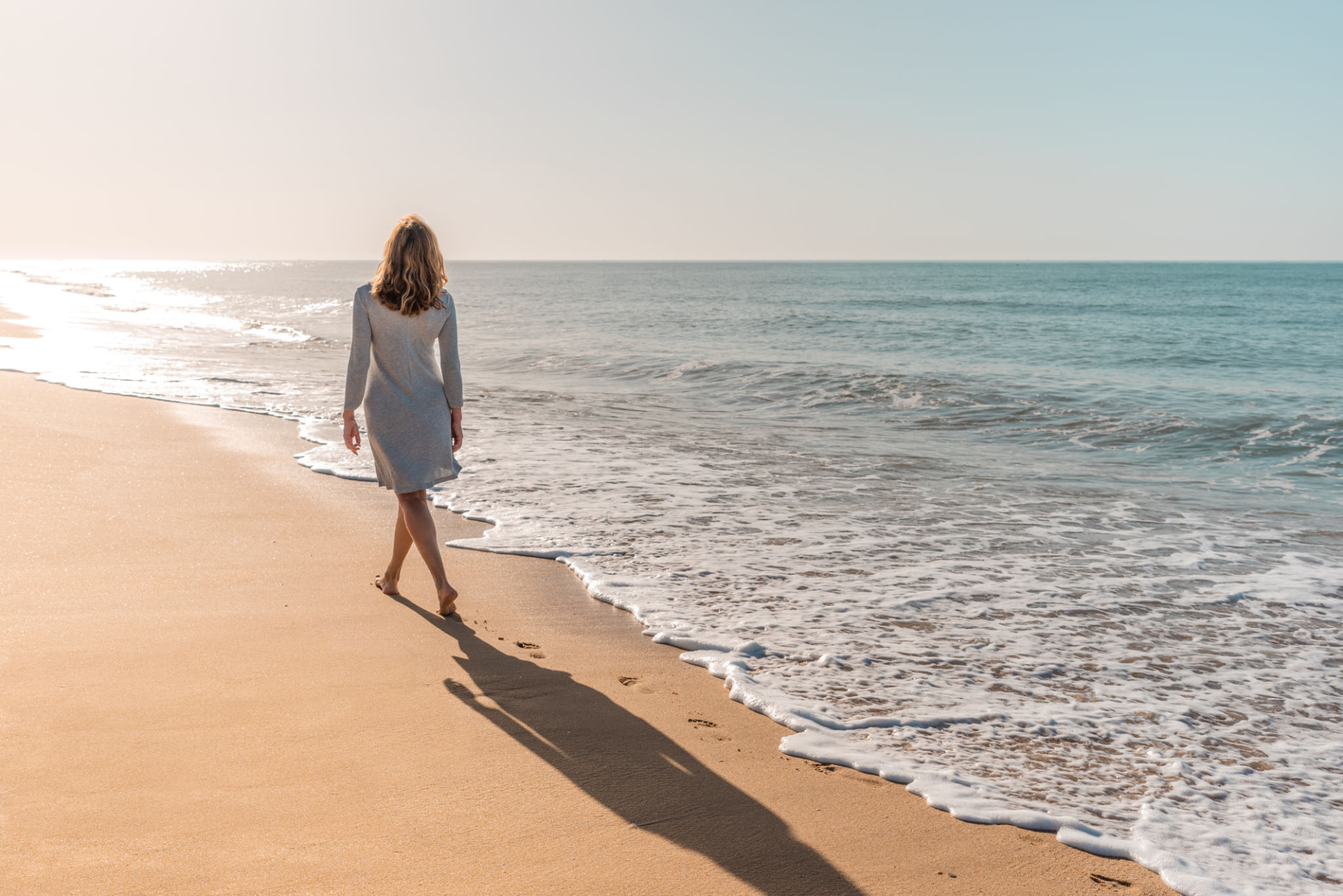 Woman walking on the beach looking at the sun Woman walking on the beach looking at the sun