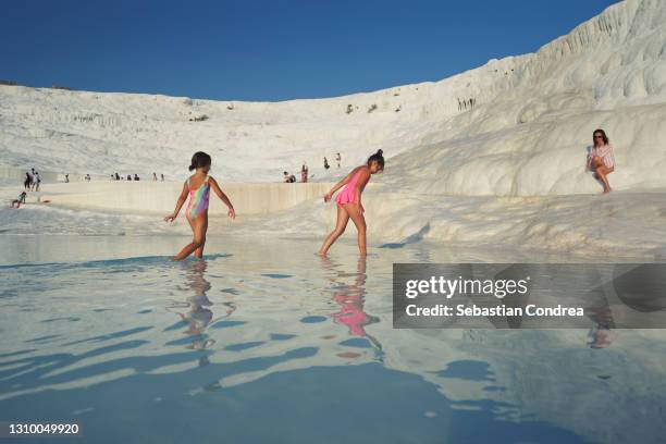 tourist girls are walking and playing on travertines of pamukkale. pamukkale's terraces are made of travertine. - pamukkale stock pictures, royalty-free photos & images