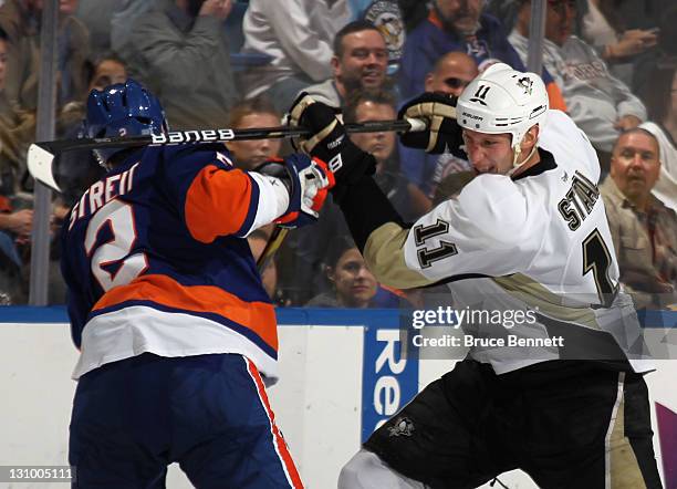 Jordan Staal of the Pittsburgh Penguins gets the stick up on Mark Streit of the New York Islanders at the Nassau Veterans Memorial Coliseum on...