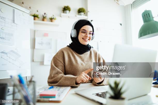 middle eastern woman working on laptop in office and having video call with partners - women religion stock pictures, royalty-free photos & images