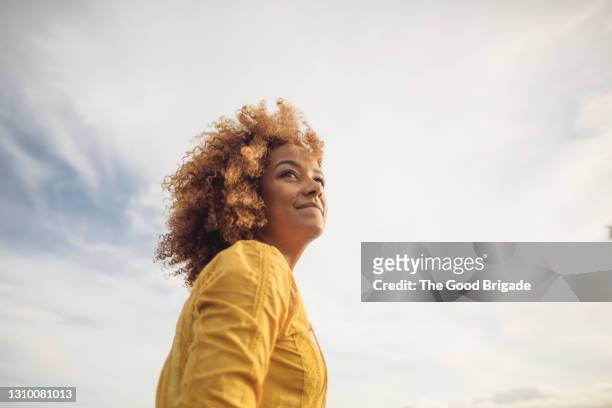low angle portrait of beautiful woman against sky - stili di vita foto e immagini stock