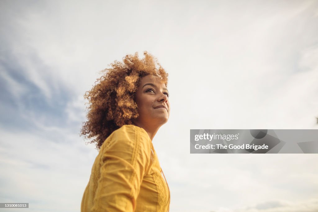 Low angle portrait of beautiful woman against sky