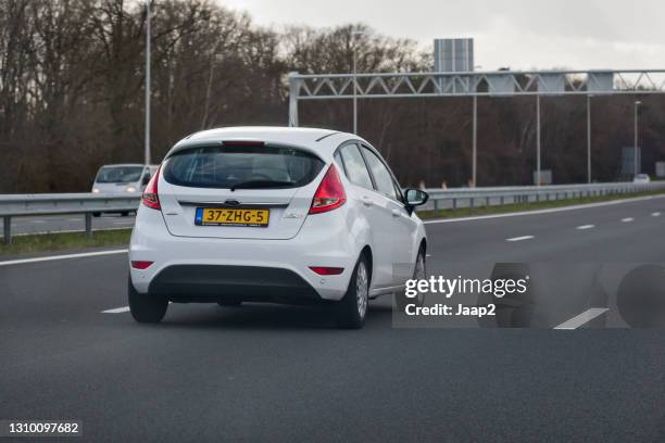 white 2012 ford fiesta driving on dutch highway a1 near holten - fiesta posterior stock pictures, royalty-free photos & images