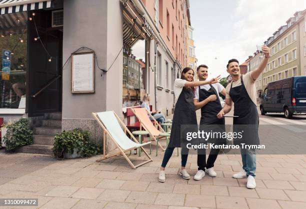 happy male and female cafe owner taking selfie on smart phone outside coffee shop - camionnette stock-fotos und bilder