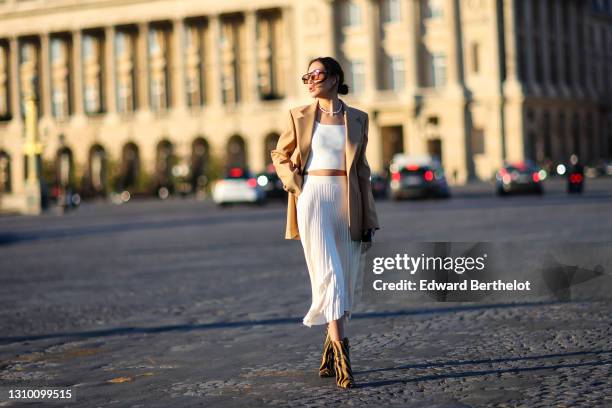 Yoshino Mia wears sunglasses from Vehla Eyewear, a pearl necklace from Amber Sceats, a beige oversized blazer jacket from Barbara Bui, a white...