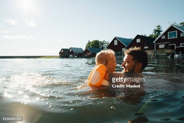 side view of smiling daughter with father in lake during vacations - gazebo stockfoto's en -beelden