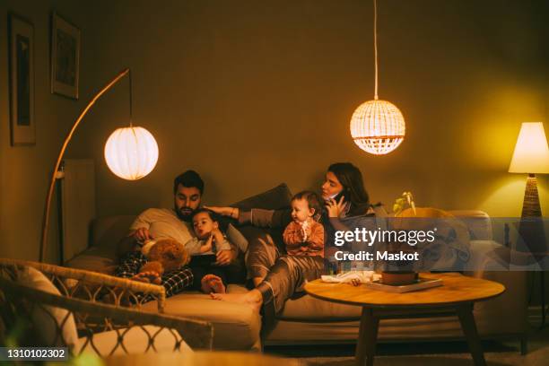 parents sitting with children in living room at night - woman home with sick children imagens e fotografias de stock