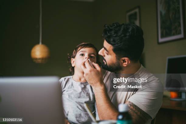 father giving nasal spray inhaler to son at home - stockholm syndrome stock pictures, royalty-free photos & images