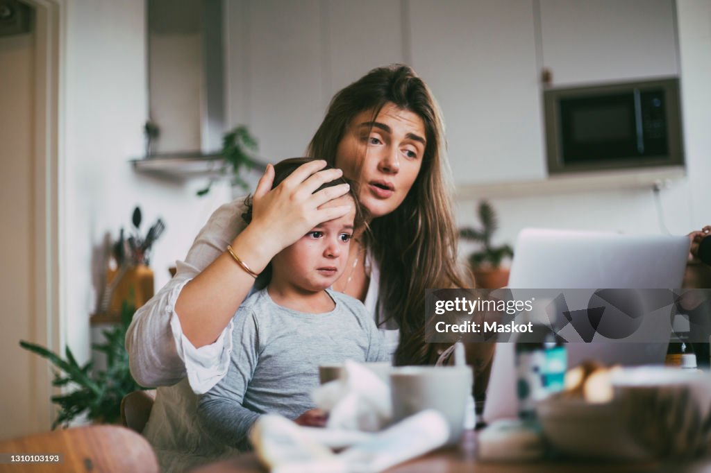 Mother with sick son taking advice on video call at home