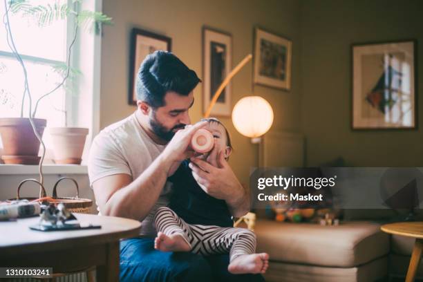 father feeding baby girl from bottle in living room at home - bébé biberon photos et images de collection