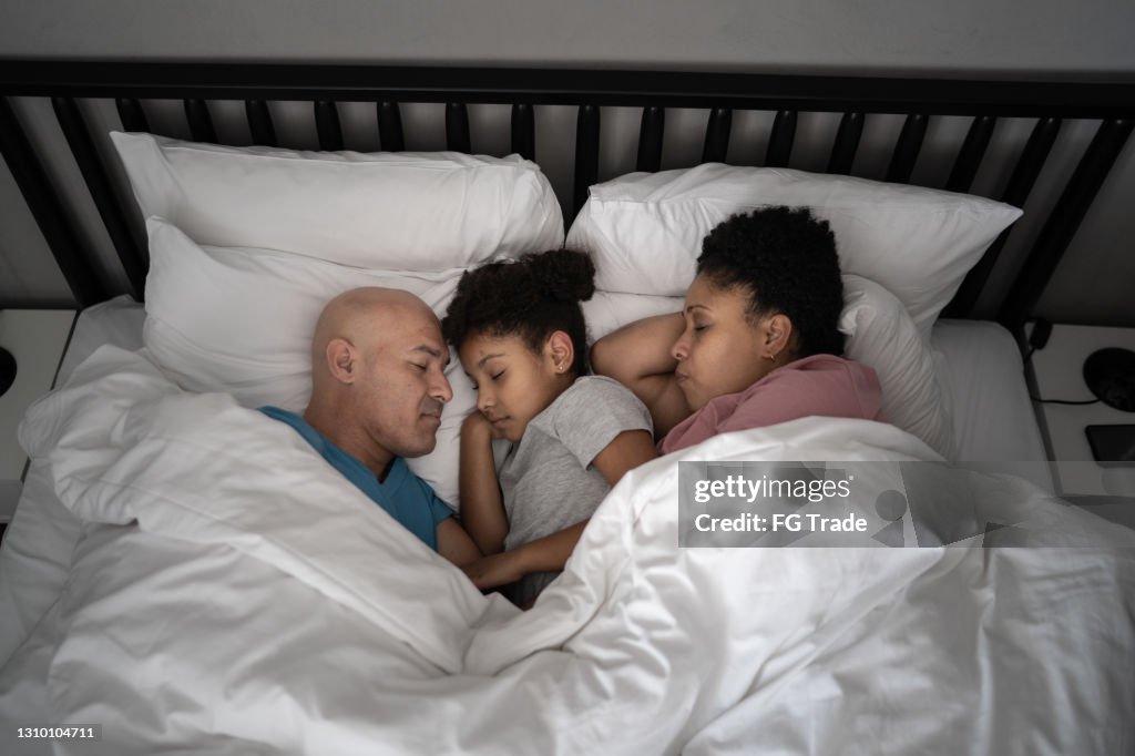 Family sleeping together in bed