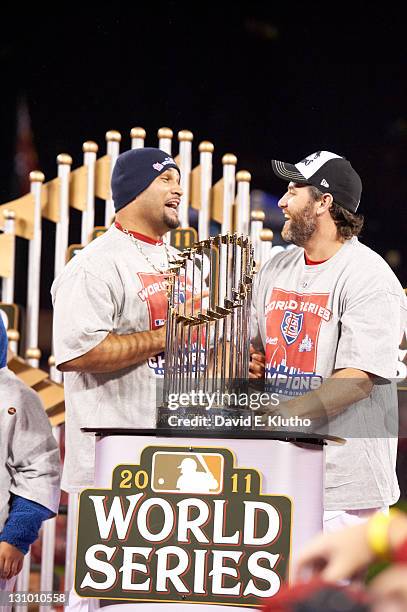 World Series: St. Louis Cardinals Lance Berkman and Albert Pujols victorious, standing next to Commissioner's Trophy on field after game vs Texas...