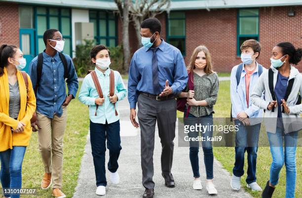 teacher, middle school students walking outside building - school principal stock pictures, royalty-free photos & images