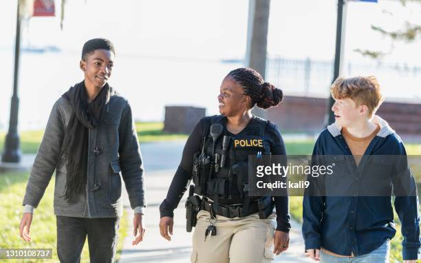policewoman in community, walking with two youths - police stock pictures, royalty-free photos & images