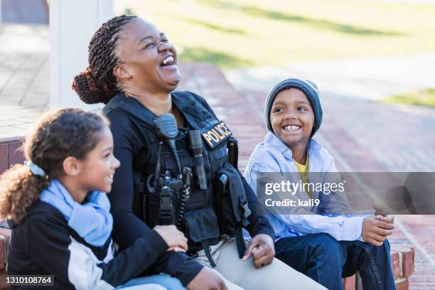 mujer policía en la comunidad, sentada con dos niños - emergency services fotografías e imágenes de stock