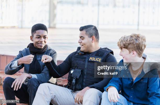 agente di polizia in comunità, seduto con due giovani - good cop foto e immagini stock