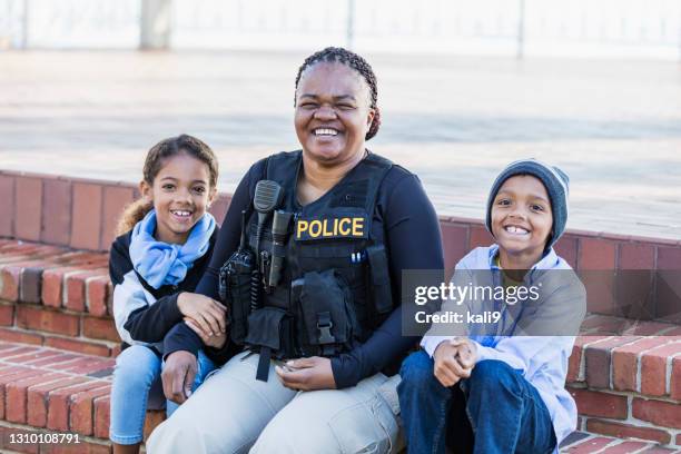 policewoman in the community, sitting with two children - community arm in arm stock pictures, royalty-free photos & images