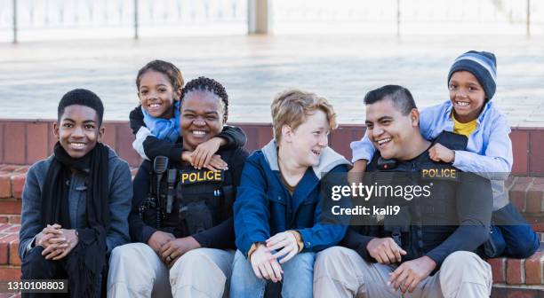 two police officers in community, sitting with children - friendly police stock pictures, royalty-free photos & images