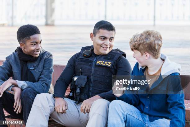 police officer in community, sitting with two youths - força policial imagens e fotografias de stock