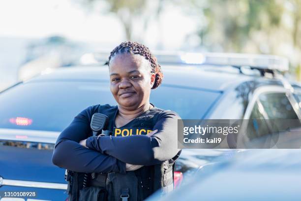 african-american policewoman next to patrol car - police woman stock pictures, royalty-free photos & images