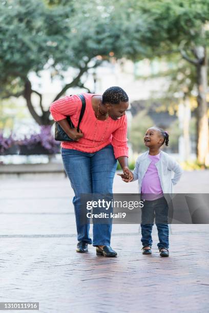 african-american mother and daughter walk in city park - black purse stock pictures, royalty-free photos & images