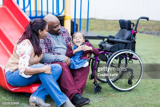 parents with wheelchair-bound daughter at playground - father-and-child-playground stock pictures, royalty-free photos & images