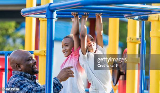 twin brothers playing on monkey bars, dad watching - boy on monkey bars stock pictures, royalty-free photos & images