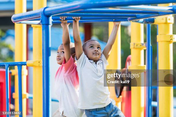 twin brothers playing on monkey bars - boy on monkey bars stock pictures, royalty-free photos & images