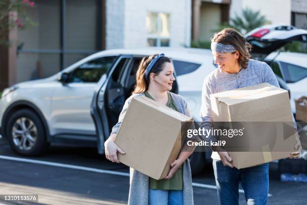 young couple moving, unloading car in parking lot - possession stock pictures, royalty-free photos & images